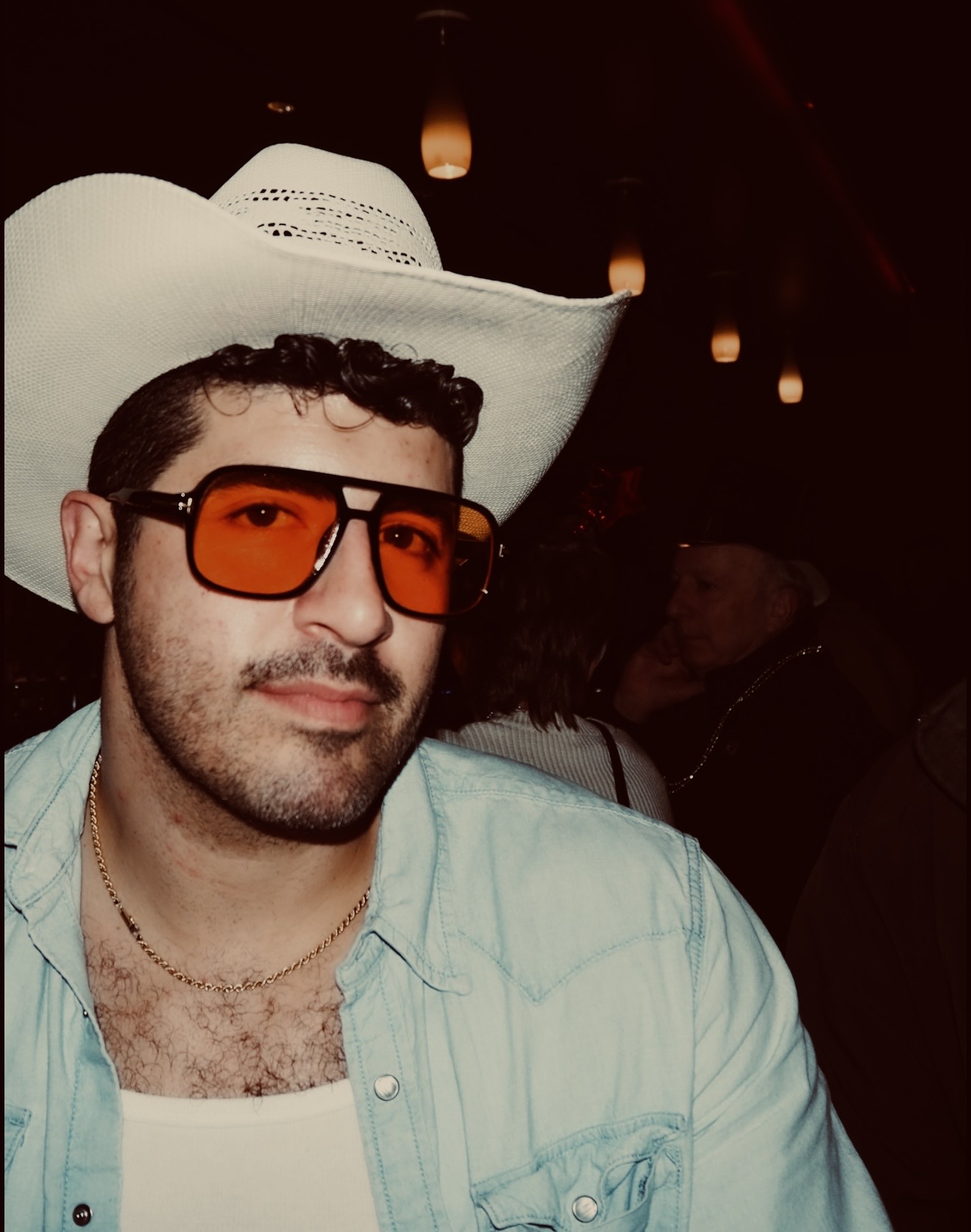 Andrew in a cowboy hat and orange shades at a bar